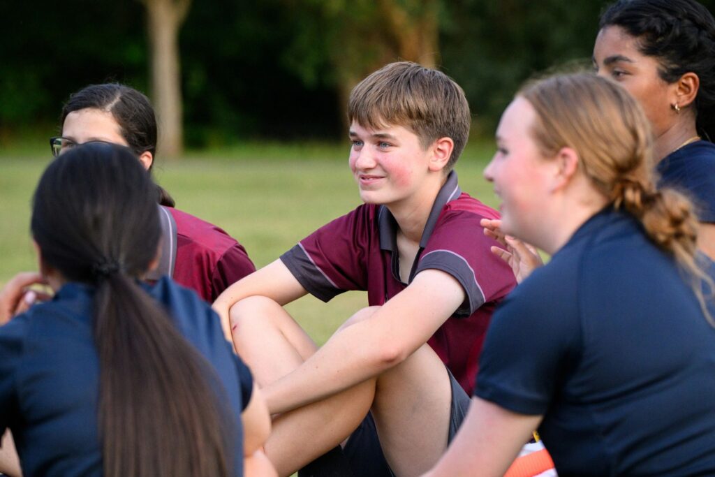 Teenage cricket players gather with their coach, encouraging one another through teamwork and leadership.