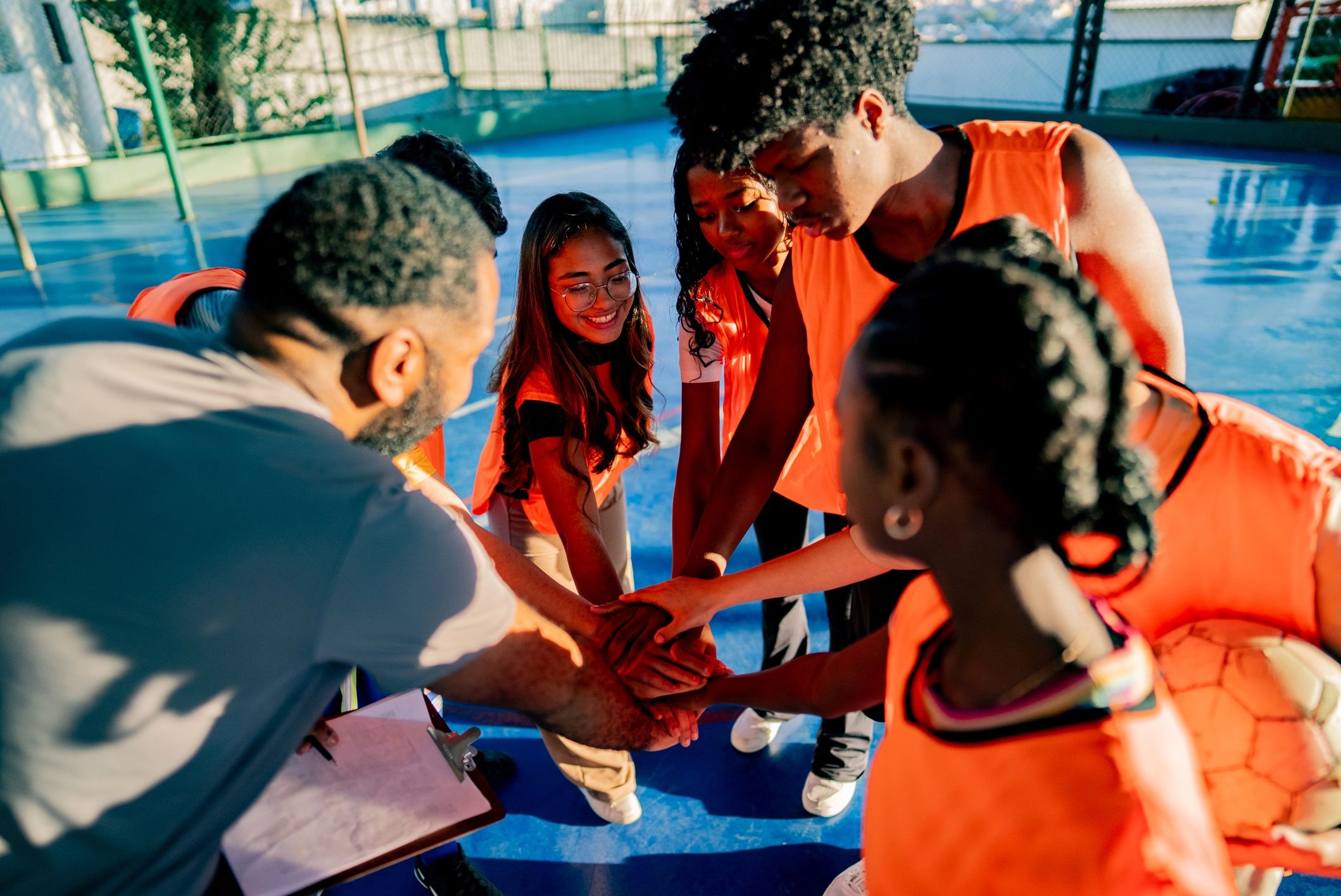 School soccer team and coach with hands together in team huddle