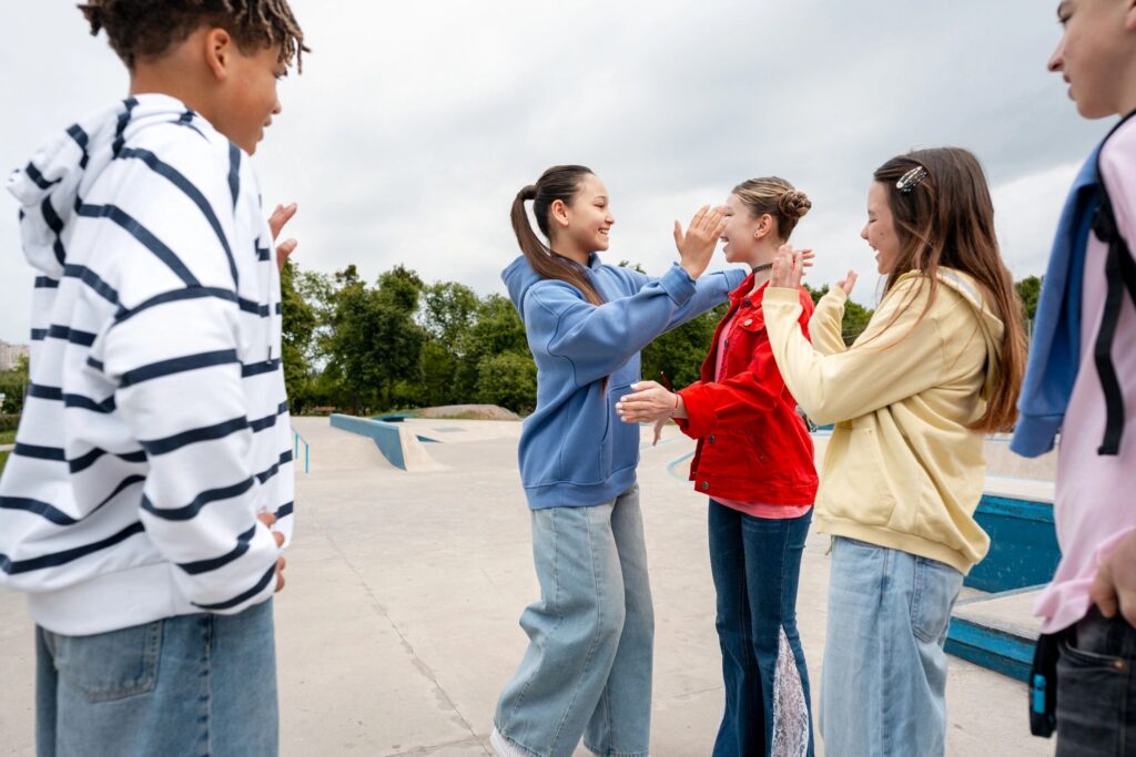 Happy teenagers enjoying friendship and laughing at skatepark